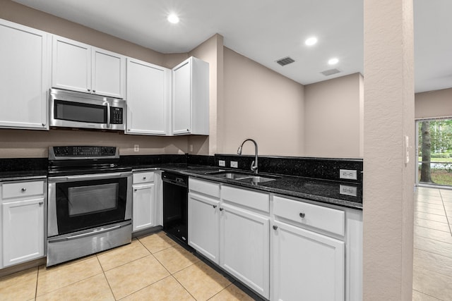 kitchen featuring appliances with stainless steel finishes, white cabinetry, sink, dark stone countertops, and light tile patterned floors