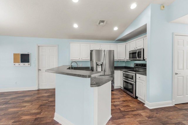 kitchen with a kitchen island with sink, visible vents, white cabinetry, appliances with stainless steel finishes, and dark countertops