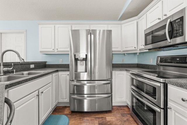 kitchen with appliances with stainless steel finishes, dark countertops, and white cabinets