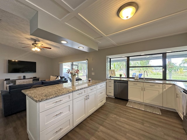 kitchen with black dishwasher, sink, white cabinets, and light stone counters