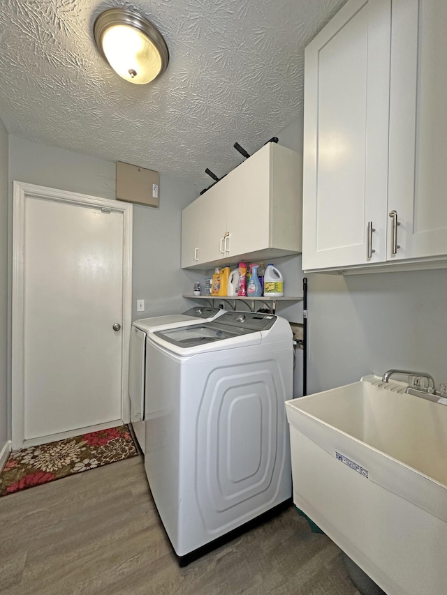 washroom featuring dark wood-type flooring, sink, cabinets, washer and dryer, and a textured ceiling