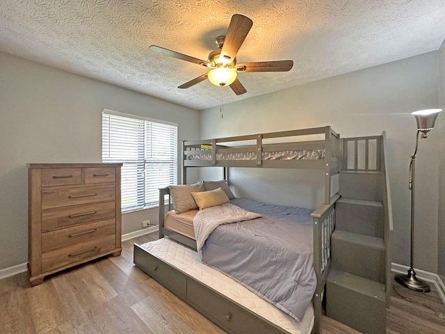 bedroom with ceiling fan, hardwood / wood-style flooring, and a textured ceiling