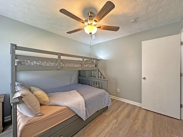 bedroom featuring ceiling fan, hardwood / wood-style floors, and a textured ceiling