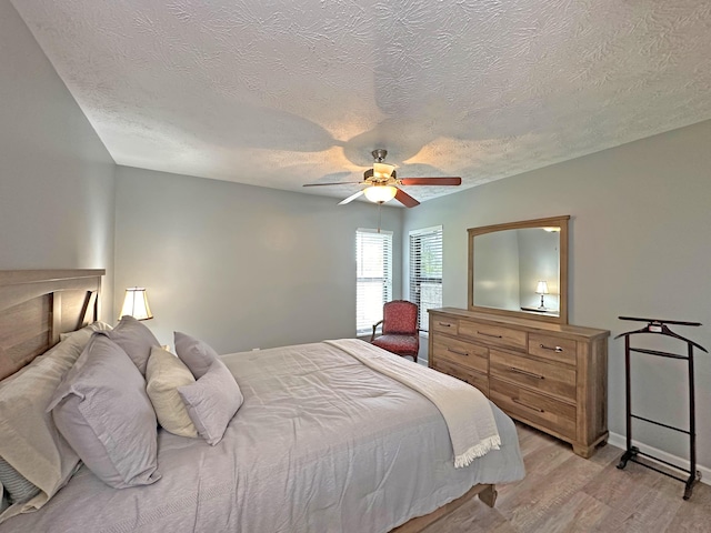 bedroom with a textured ceiling, light hardwood / wood-style flooring, and ceiling fan