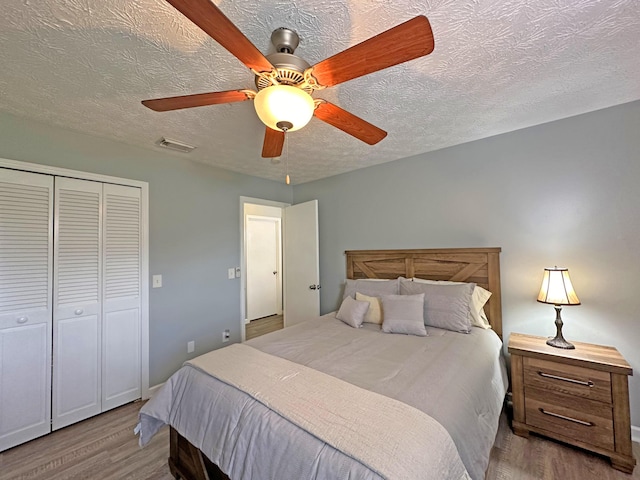 bedroom featuring hardwood / wood-style floors, a textured ceiling, a closet, and ceiling fan