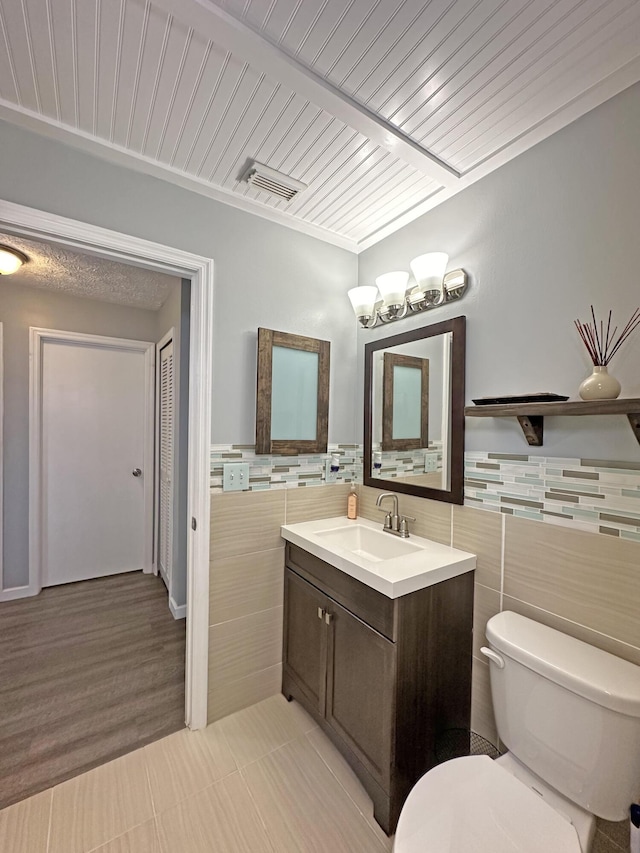 bathroom with tile patterned floors, vanity, toilet, and tile walls