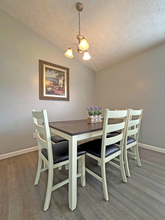 dining area with lofted ceiling, an inviting chandelier, a textured ceiling, and dark hardwood / wood-style flooring