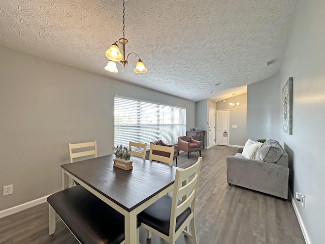 dining space with hardwood / wood-style flooring, lofted ceiling, a textured ceiling, and a notable chandelier