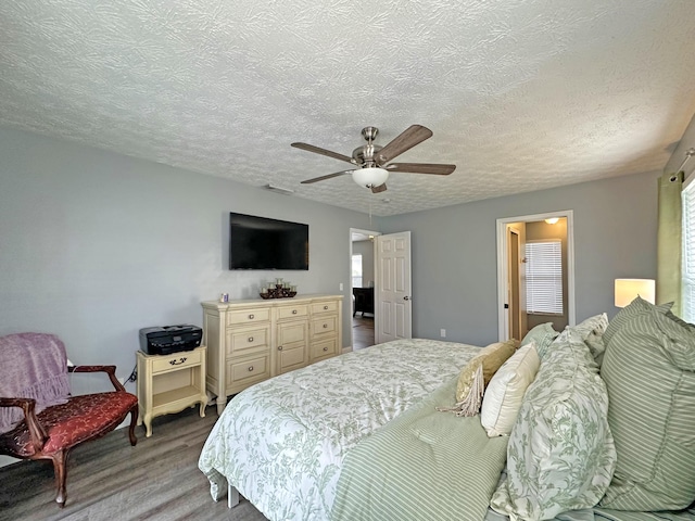 bedroom featuring ceiling fan, light hardwood / wood-style floors, and a textured ceiling