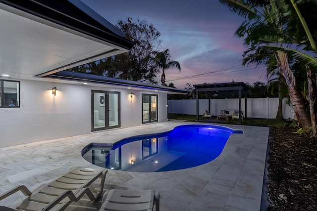 pool at dusk featuring a patio area