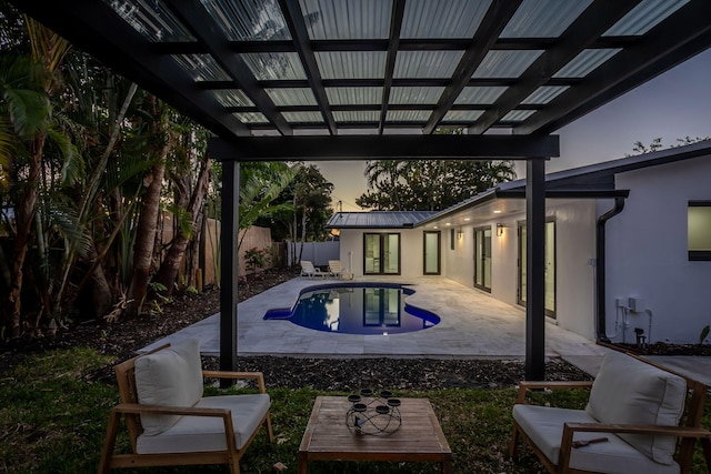 pool at dusk featuring a pergola and a patio area