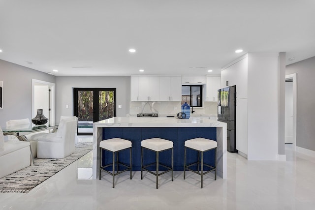 kitchen featuring a spacious island, french doors, a breakfast bar area, white cabinetry, and black fridge