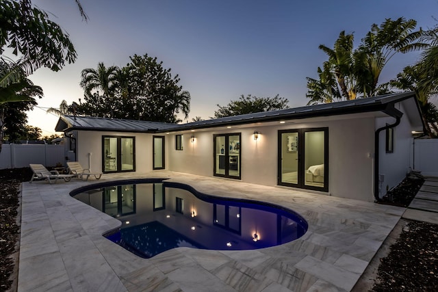 pool at dusk with a patio area