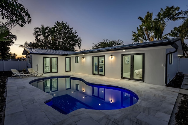 pool at dusk with a patio area