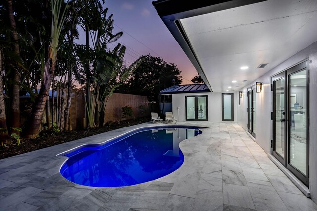 pool at dusk with a patio area