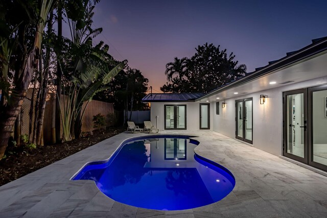 pool at dusk with a patio area