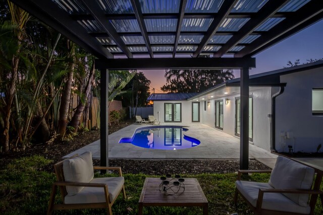 pool at dusk with french doors and a patio