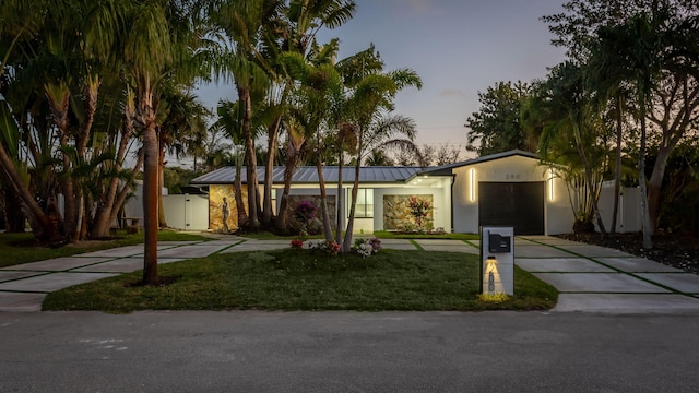 ranch-style house with a garage and a lawn