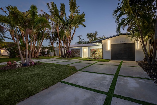 view of front of home with a garage and a lawn