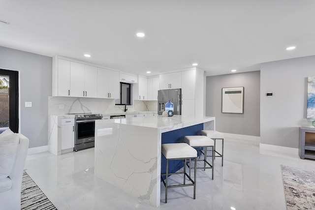 kitchen with appliances with stainless steel finishes, a breakfast bar, sink, white cabinets, and a center island