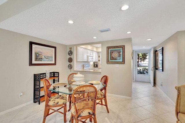 tiled dining space with a textured ceiling