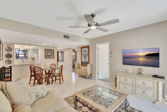 tiled living room featuring ceiling fan and a textured ceiling