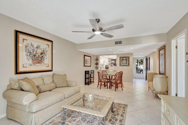 living room featuring ceiling fan, light tile patterned floors, and a textured ceiling