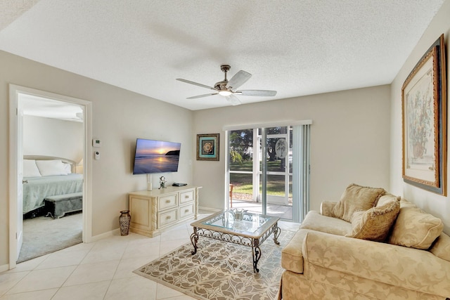 living room with light tile patterned flooring, ceiling fan, and a textured ceiling