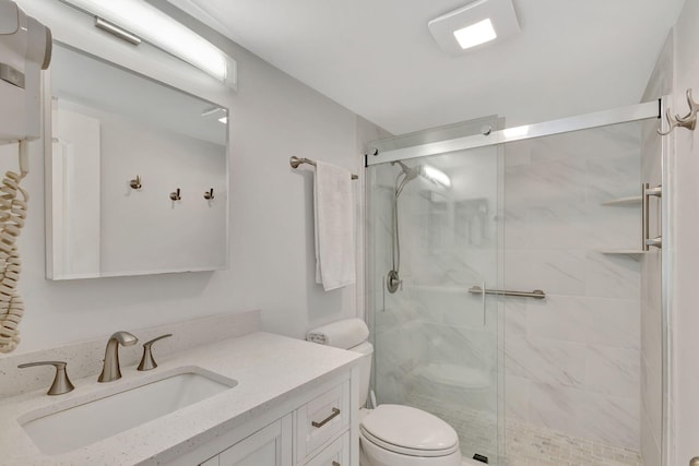 bathroom featuring vanity, a shower with door, and toilet