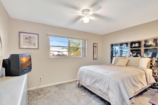 bedroom with ceiling fan, light colored carpet, and a textured ceiling