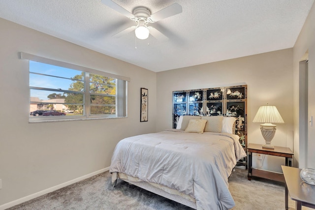 bedroom with ceiling fan, carpet flooring, and a textured ceiling