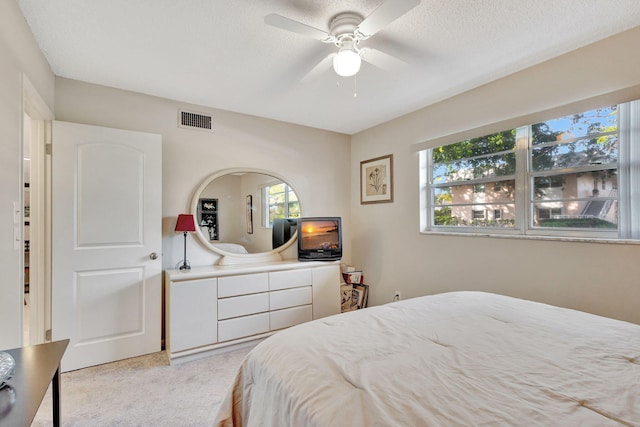 carpeted bedroom with ceiling fan and a textured ceiling