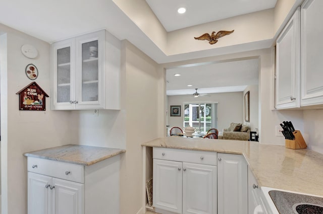 kitchen featuring light stone counters, ceiling fan, white cabinets, and range