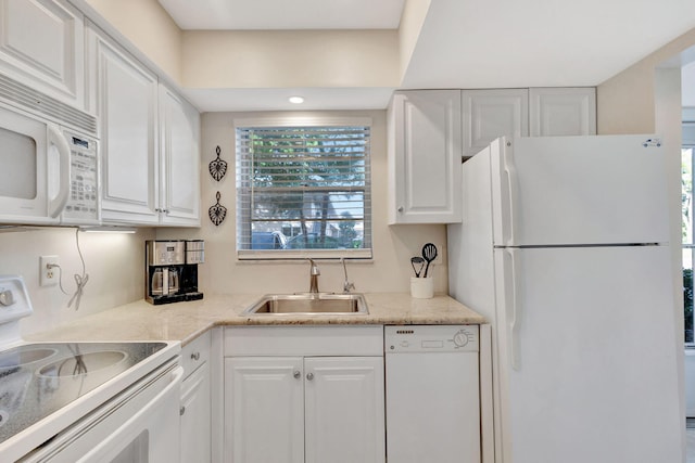 kitchen with white cabinetry, white appliances, light stone countertops, and sink