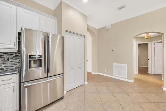 kitchen with light tile patterned flooring, white cabinetry, ornamental molding, stainless steel fridge, and backsplash