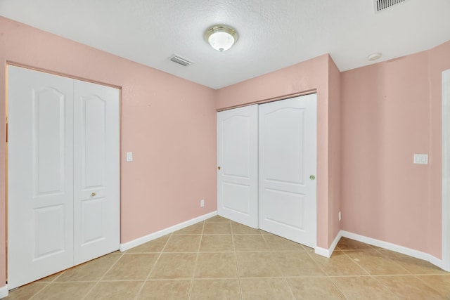 unfurnished bedroom featuring a textured ceiling and light tile patterned floors