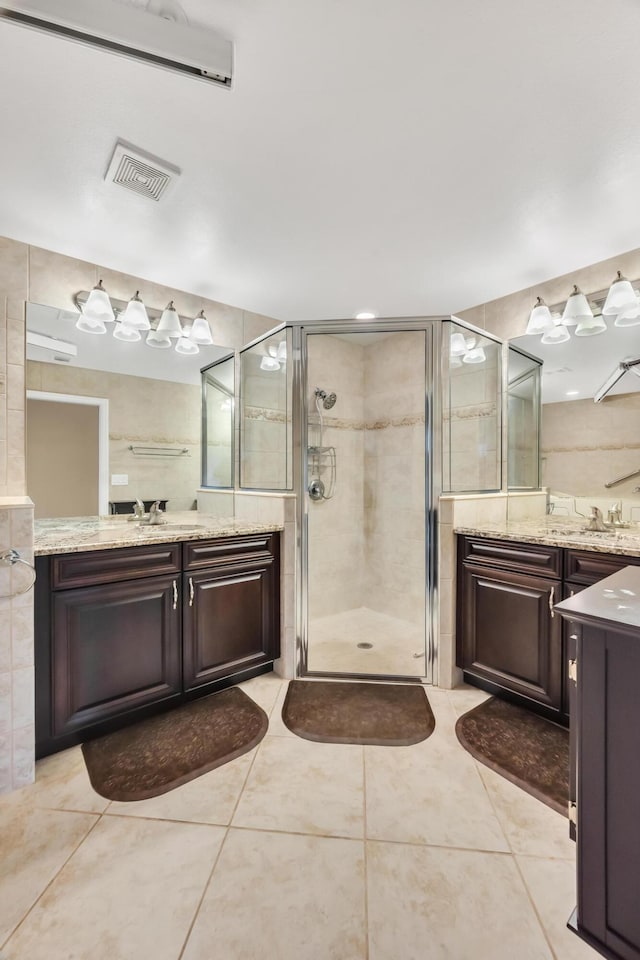 bathroom with tile patterned floors, vanity, an enclosed shower, and tile walls