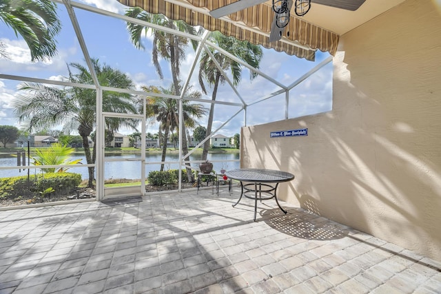 view of patio / terrace featuring glass enclosure and a water view