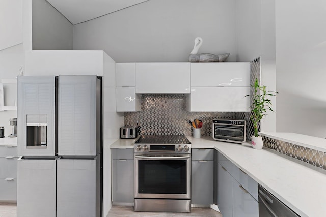 kitchen featuring white cabinets, stainless steel appliances, decorative backsplash, and gray cabinetry