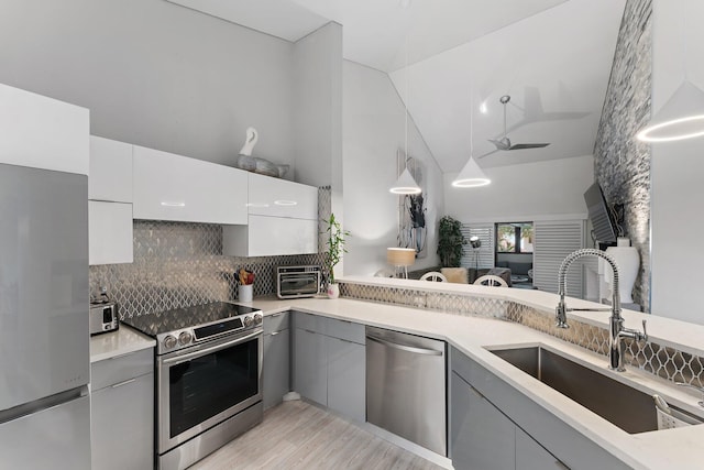 kitchen featuring sink, appliances with stainless steel finishes, white cabinetry, backsplash, and hanging light fixtures