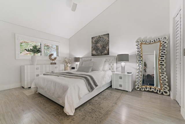 bedroom with ceiling fan, high vaulted ceiling, and light hardwood / wood-style floors