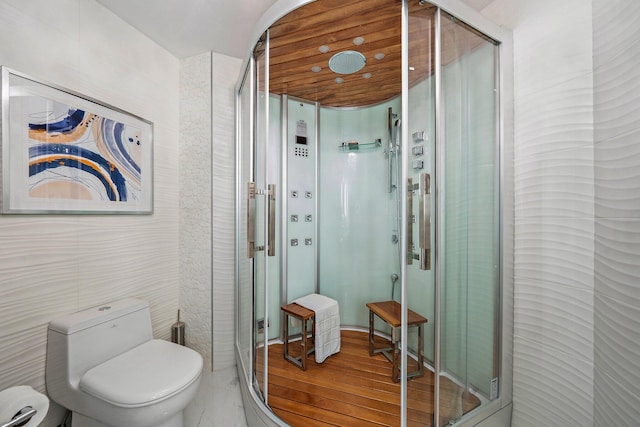 bathroom featuring wood-type flooring, toilet, and a shower with shower door