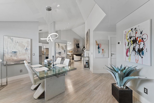 dining area featuring high vaulted ceiling, an inviting chandelier, and light hardwood / wood-style flooring