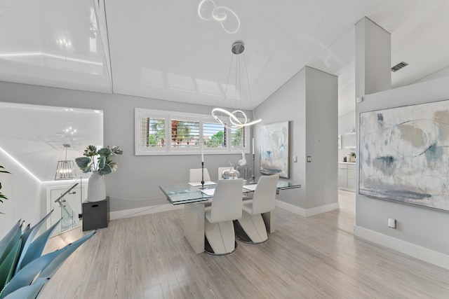 dining space with lofted ceiling, a notable chandelier, and light hardwood / wood-style floors