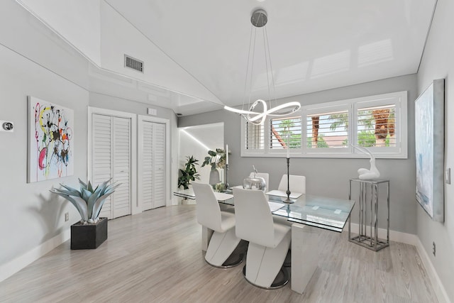 dining space featuring a notable chandelier, lofted ceiling, and light wood-type flooring