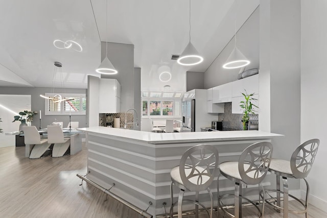 kitchen featuring backsplash, plenty of natural light, kitchen peninsula, and white cabinets