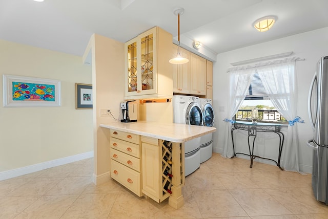 kitchen with pendant lighting, light tile patterned floors, stainless steel refrigerator, independent washer and dryer, and light brown cabinetry