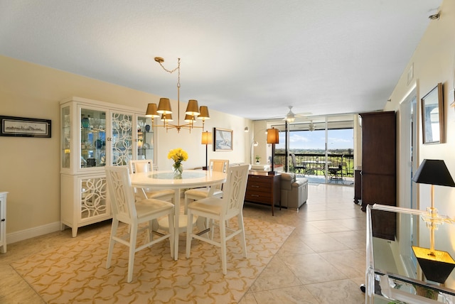 tiled dining area featuring ceiling fan with notable chandelier and floor to ceiling windows