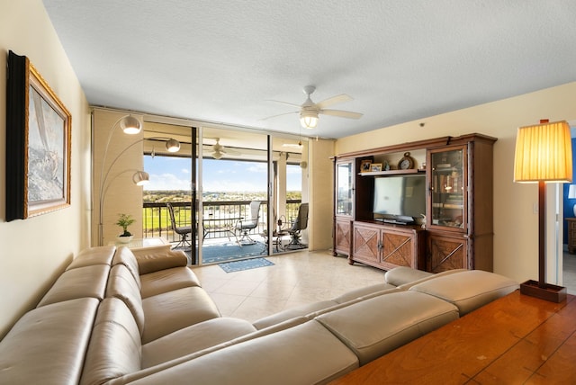 tiled living room featuring ceiling fan, a wall of windows, and a textured ceiling