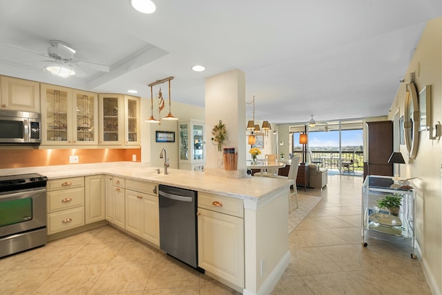 kitchen featuring hanging light fixtures, stainless steel appliances, kitchen peninsula, and ceiling fan